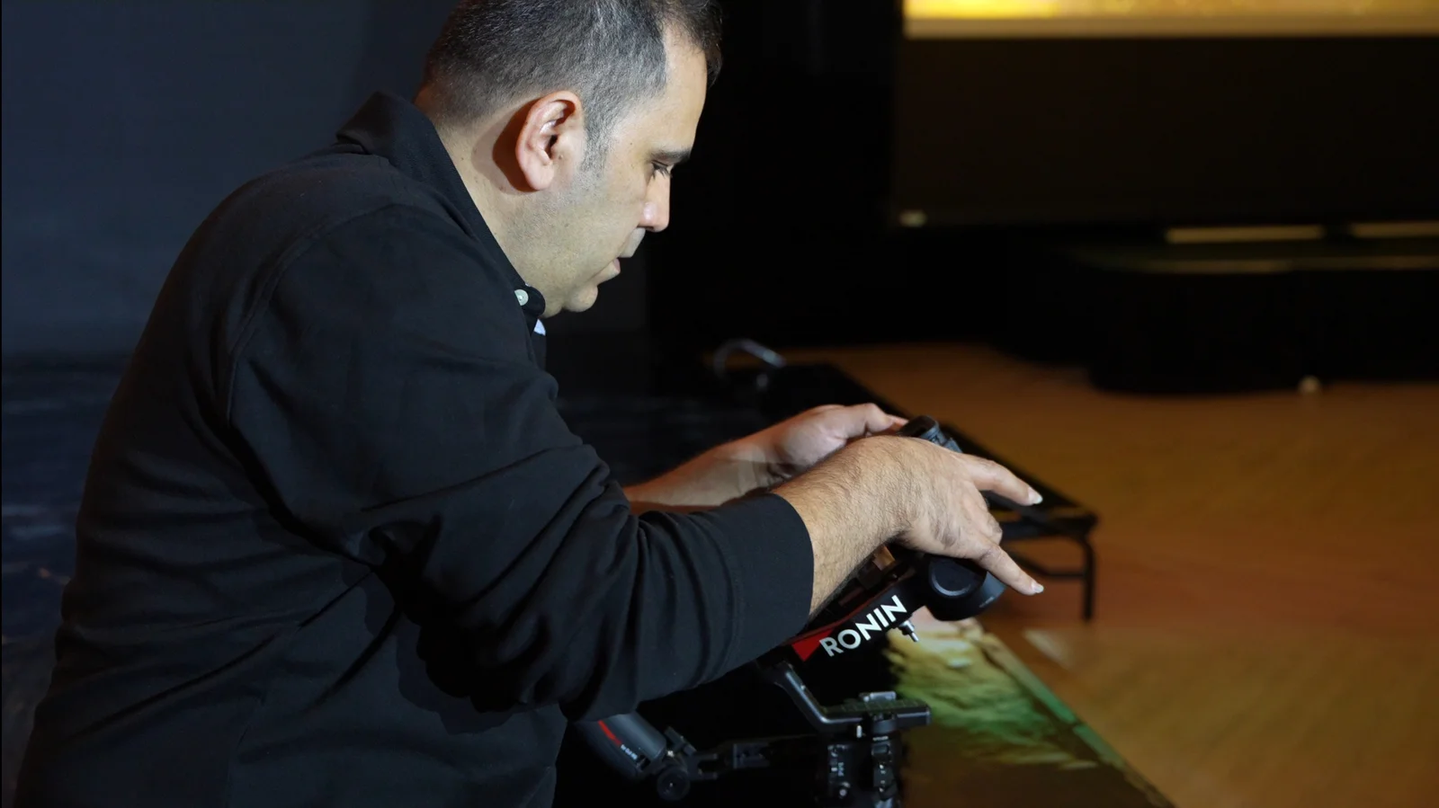 Camera operator adjusting a Ronin stabilizer beside the stage