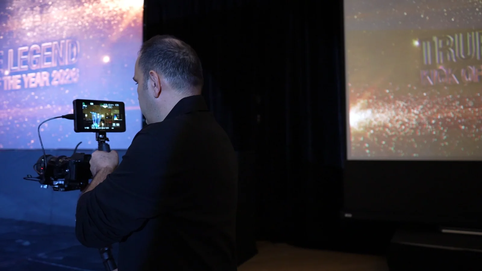 Camera operator filming beside the kickoff event screens