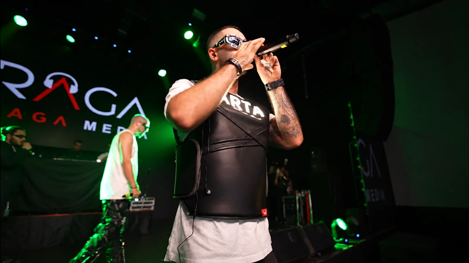 Performer singing into a microphone under green stage lighting