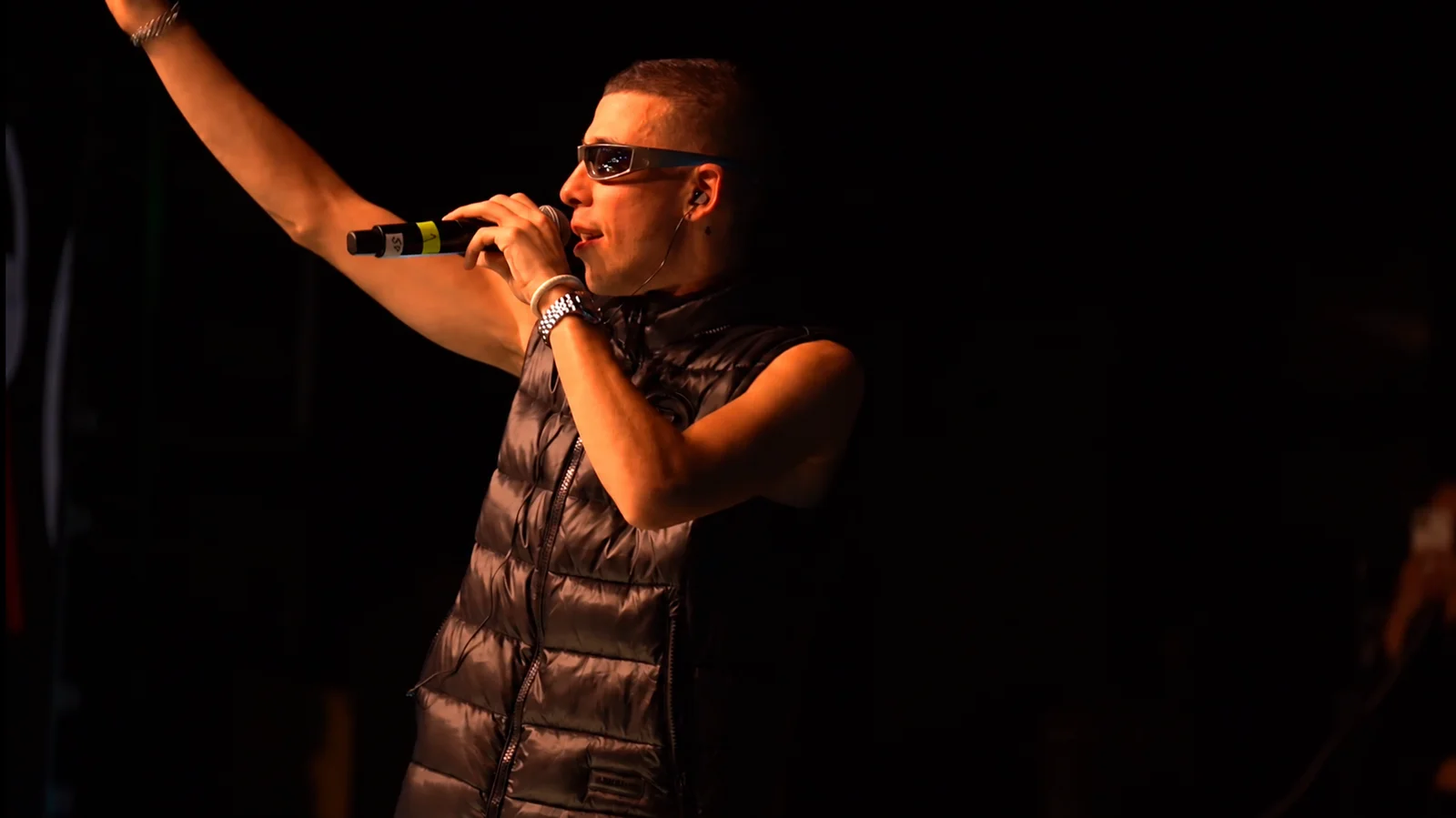 Performer holding a microphone under warm stage lighting